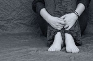 Deprese, osoba sedí na zemi se složenými rukami kolem nohou