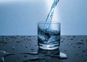 Přelévající se voda z láhve do sklenice.