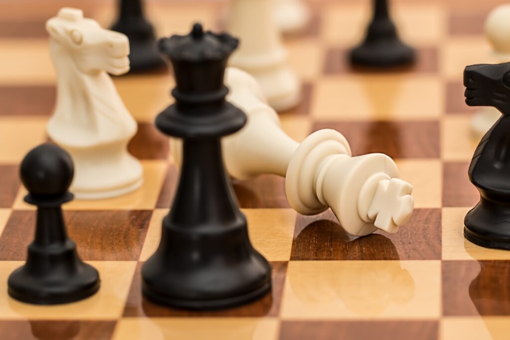 Šachovnice a a ní stojí dáma pěšák a koně. Bílý král v šach-matu