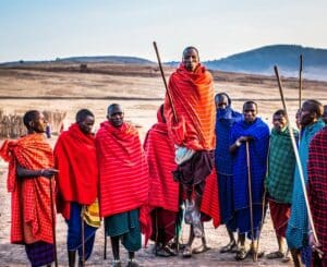 Domorodí Afričané seskupeni v řadě, oblečeni v červeném a modrém.