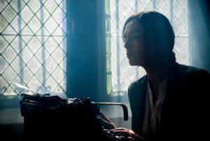 Žena zavřená za okny, píšící na psacím stroji.