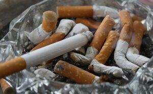 Množství vykouřených cigaret ve skleněném popelníku.