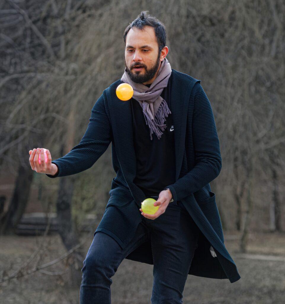 Muž, který žongluje se třemi žlutými míčky na veřejnosti.