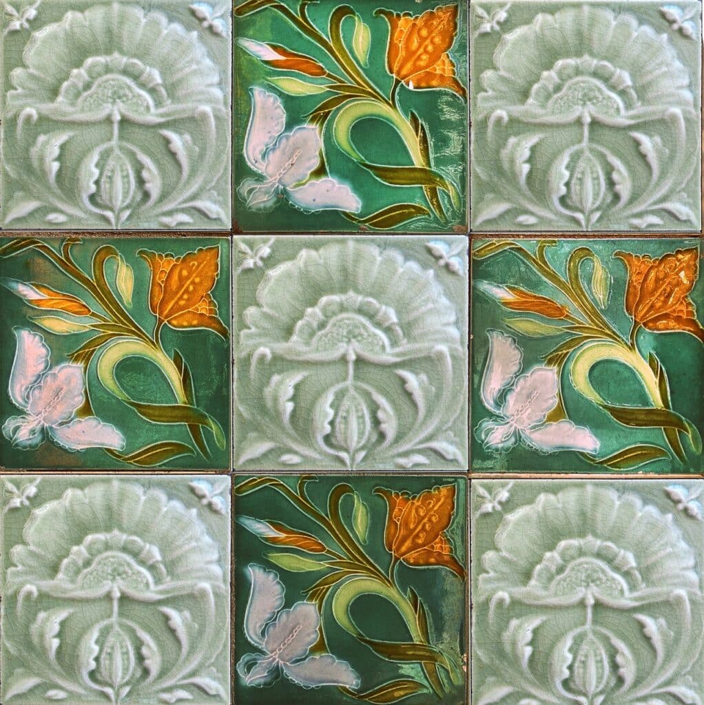 Zelená keramická dlažba s květovanými prvky.