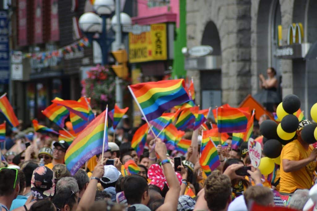Pochod LGBT komunty na pride, s barevnými vlaječkami.