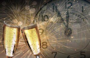 Dvě sklenky se šampaňským, ohňostroj a odpočet hodin do Nového roku v Rakousku.