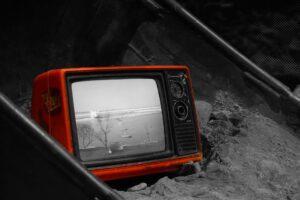 Červená televize s černobílým promítáním v písku.