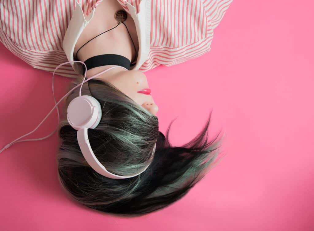 Žena, která leží, má nasazené sluchátka a poslouchá hudbu.