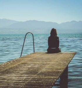 Žena sedící na molu u jezera